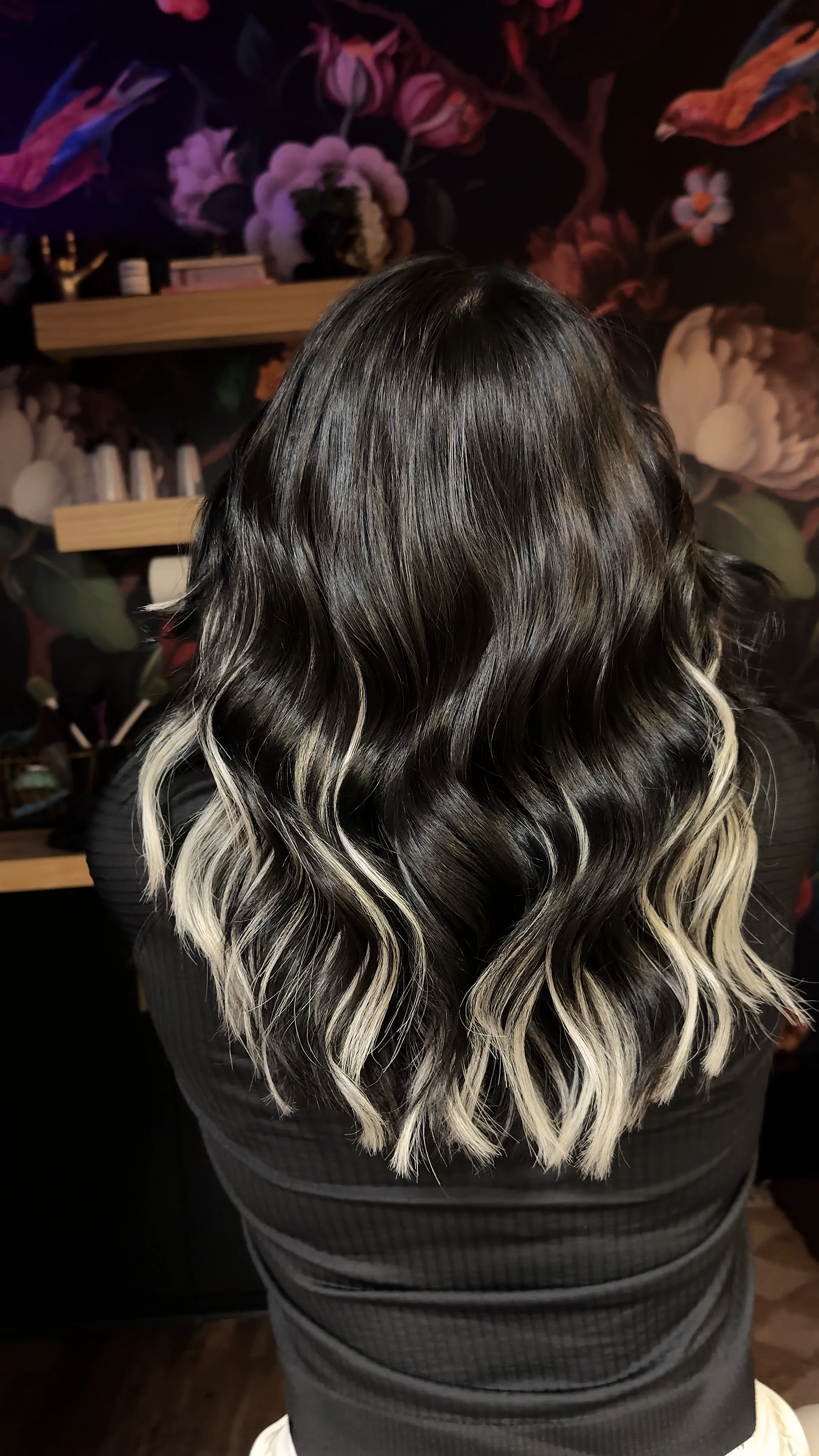 Black hair with platinum money pieces against the dark floral mural